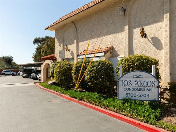 Front view of a condominium building with a sign reading 'Los Arcos Condominiums'.