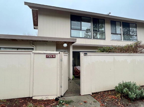 Front view of a two-story house with beige siding and a gated entrance.