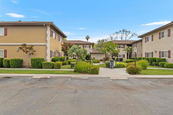 Front view of a two-story apartment building with landscaped pathway.