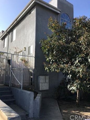 Front view of a multi-story residential building with a gated entrance.