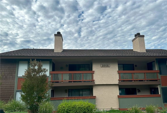 Front view of a two-story building with balconies and chimneys.