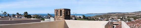 Panoramic view of coastal area with rooftops and ocean.