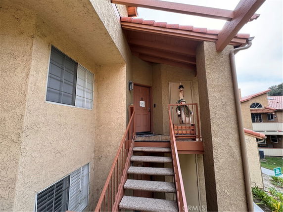 Entrance of a residential building with staircase and overhanging roof.