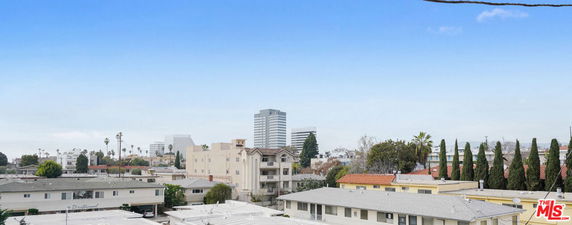 Panoramic view of a neighborhood with multiple residential and commercial buildings under a clear blue sky.