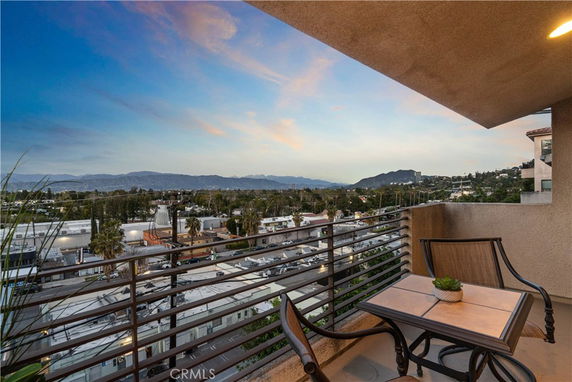 Balcony view overlooking urban area with distant mountains and a colorful sky.