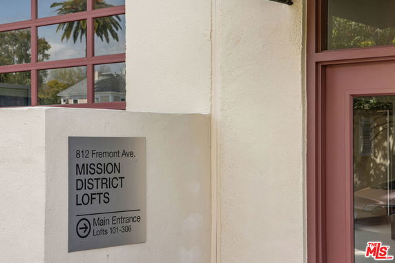 Front view of a building with the sign 'Mission District Lofts' and a glass window.
