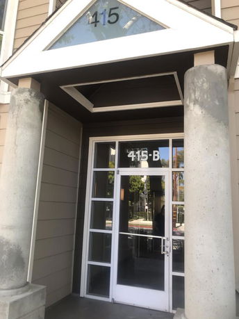 Front view of a building entrance with large columns and glass door.