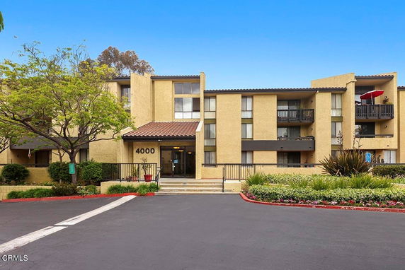 Front view of a multi-story building with balconies and an entrance at the center.