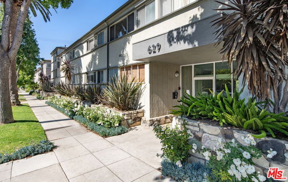 Front view of a multi-story building with a walkway and landscaped plants.