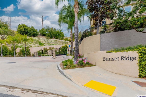 Front view of a gated community entrance with a sign that says 'Sunset Ridge'.