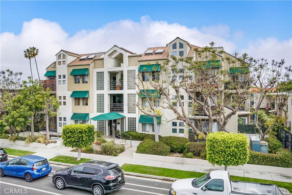 Front view of a multi-story residential building with green awnings and balconies.