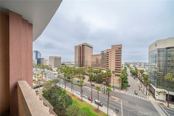 Urban view from a building balcony, showing a cityscape with tall buildings and palm-lined streets.