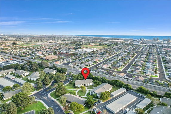 Panoramic view of a residential area with houses, roads, and a visible coastline in the distance.