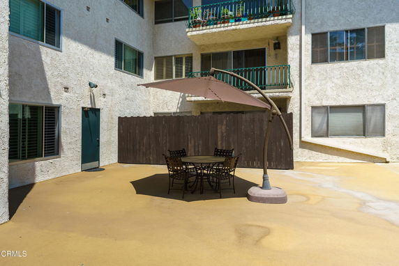 Patio area outside a multi-story building with a table and umbrella.