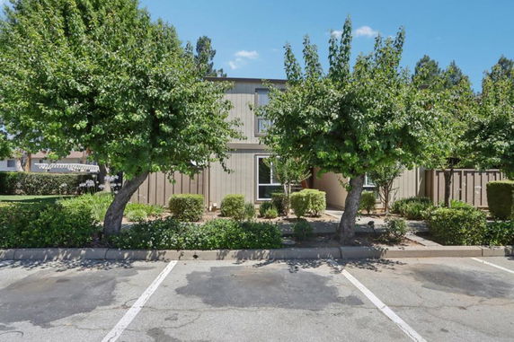 Front view of a building with adjacent parking area and landscaped trees.