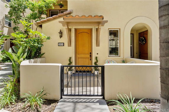 Front view of a house with a wooden door, small porch, and decorative plants.