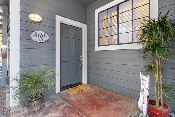 Front view of a house entrance with a blue door and house number plaque.