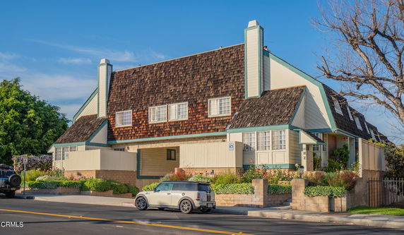 Front view of a multi-story house with a sloped roof and two chimneys.