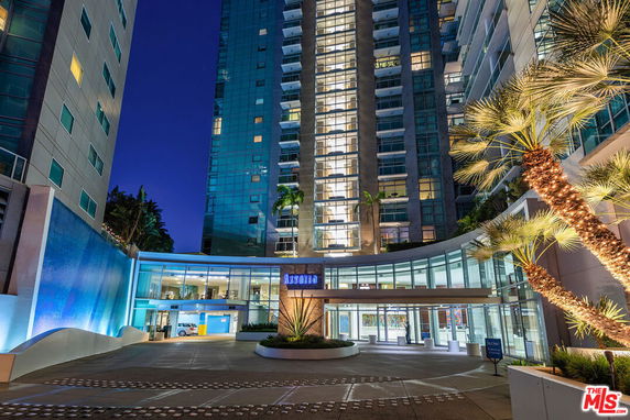 Front view of a modern high-rise building at night with illuminated entrance.
