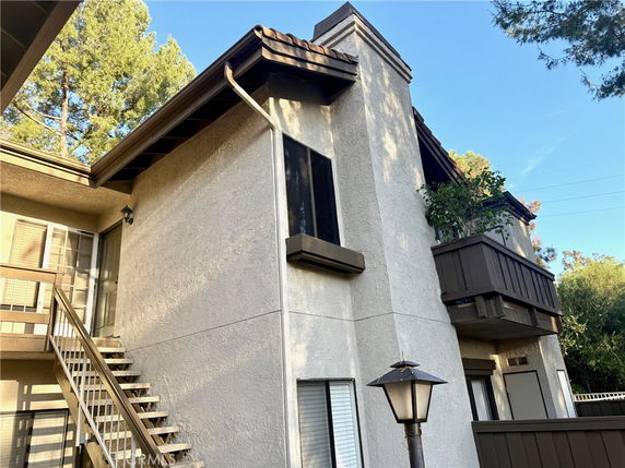 Front view of a multi-story building with a small balcony and exterior staircase.