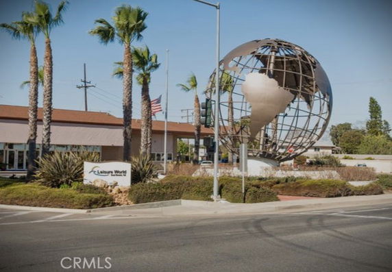 Front view of a building with a large globe sculpture and palm trees.