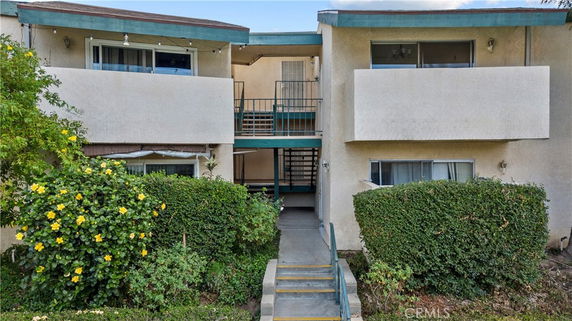 Front view of a two-story residential building with balconies and staircases.