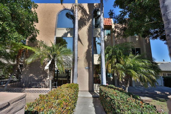 Front view of a multi-story building with large arched windows and palm trees.