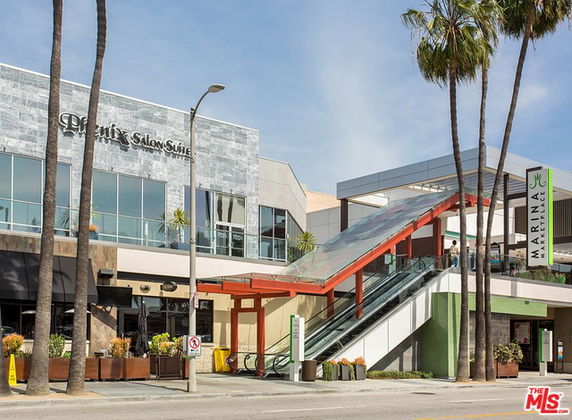 Front view of a commercial building with a salon suite and an escalator entrance.