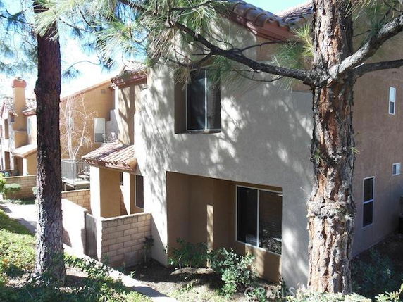 Front view of a two-story house with a shaded entrance and stucco finish.
