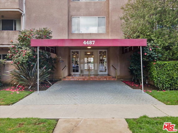 Entrance of a building with a red canopy and glass doors.