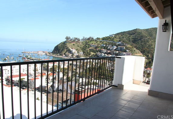 Balcony view overlooking a coastal town and hillside.