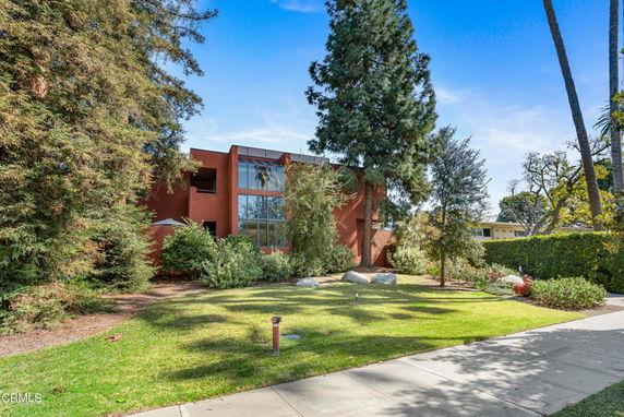 Front view of a modern two-story house with large windows and a landscaped garden.