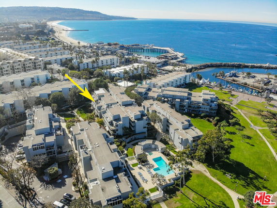 Aerial panoramic view of a residential complex near a coastline and marina.