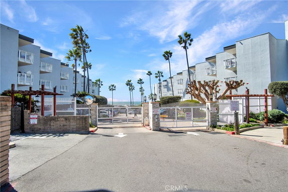 Front view of a multi-story apartment complex with balconies, surrounded by palm trees.