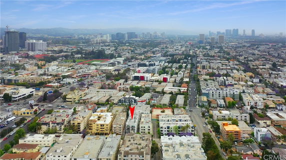 Aerial view of an urban area with multiple buildings and a city skyline in the background.