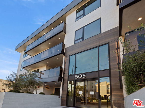 Front view of a modern multi-story building with large windows and balconies.
