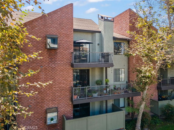 Front view of a multi-story building with brick and stucco facade and balconies.