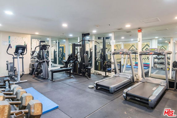 Indoor gym area with various exercise equipment including treadmills and weights.