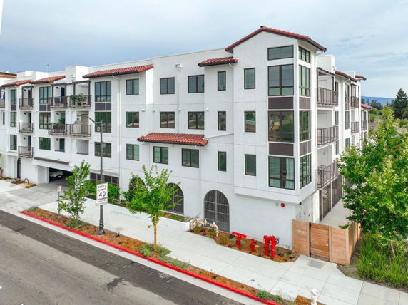 Front view of a multi-story residential building with balconies and a tiled roof.