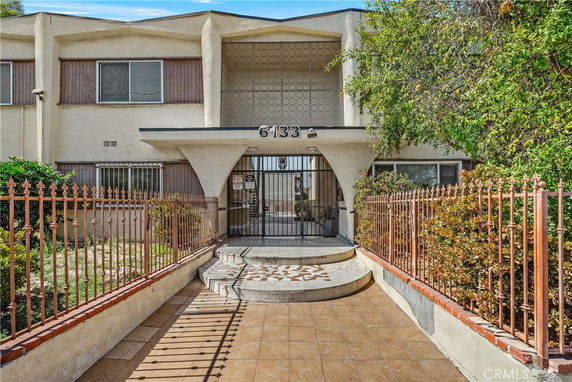 Front view of a two-story building with a gated entrance and patterned fence.