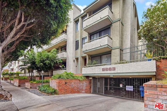 Front view of a multi-story residential building with balconies and a gated entrance.
