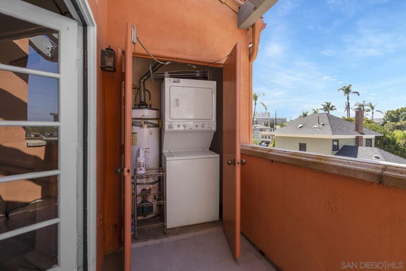 Outdoor view of a small utility closet with a stacked washer and dryer unit on a balcony.