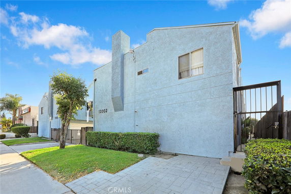 Side view of a multi-story building with light blue exterior and a gated entry.