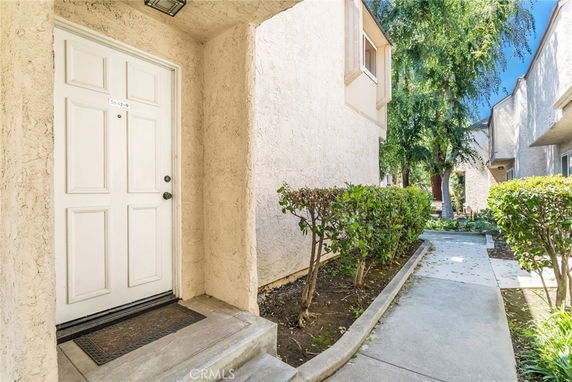Front view of a residential building entrance with a white door and pathway.