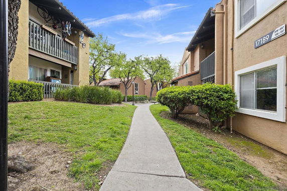 Pathway between apartment buildings with balconies and greenery.