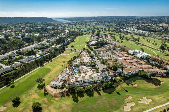 Aerial view of residential area and golf course with surrounding landscape.