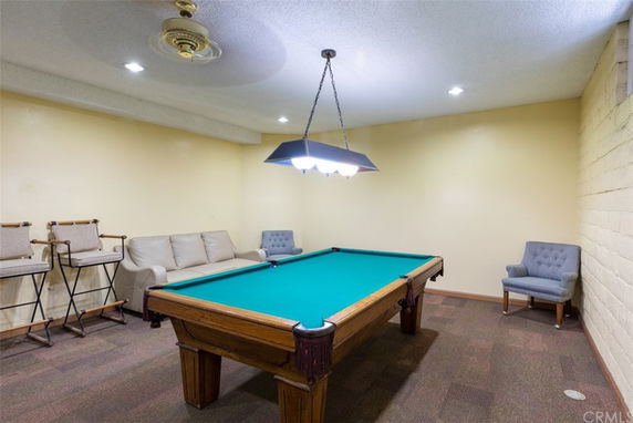 Room with a pool table, chairs, and a ceiling light.