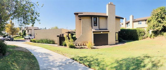 Side view of a two-story house with a chimney and brown roof.