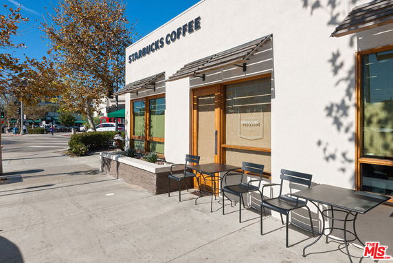 Front view of a coffee shop with an outdoor seating area and signage.
