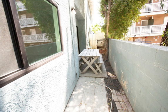 Narrow outdoor area with concrete and brick flooring alongside a building.